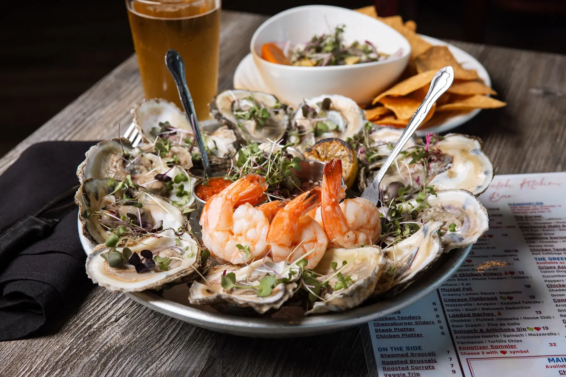 Oyster platter with raw oysters, cocktail shrimp, lemon, and microgreens
